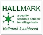 The Village Hall Green Hallmark star logo with text: “a quality standard scheme for village halls, Hallmark 2 achieved”.